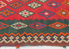 Diagonal diamonds on a powerful undulating red ground. The field is surrounded by a wide inner border with thinner diamonds on the sides and alternating triangles on the ends against a desirable and enchanting green ground. The whole is framed by a tightly rendered but somewhat erratic laleh abbasi border and finished with puzzle piece banded skirt borders. The edges are finished with candy cane selvedges in orange and blue with the occasionally poof of yarn Qashqai