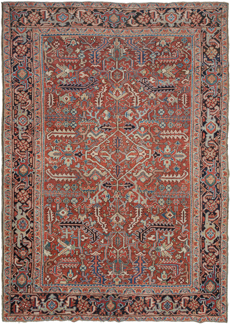 This Heriz rug was handwoven in Northwest Iran during the second quarter of the 20th century.  It features an allover design of geometric palmettes and large serrated leaves in blues, green, coral, gold, black and ivory on an undulating brick ground. All over designs are less common on Heriz rugs which most often feature large central medallions. The main border is composed of a rosette and outstretched arm palmette border on a surmah ground.