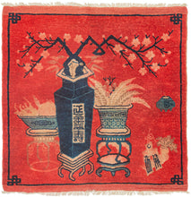 This Ningxia rug was handwoven in China during the first quarter of the 20th century.

The main design is composed of various porcelain vases filled with fruit and plants such as cherry blossoms on wooden stands.This red tone is very auspicious and often associated with prosperity. It is framed by a thin blue border that forms an endless knot symbol at each corner.