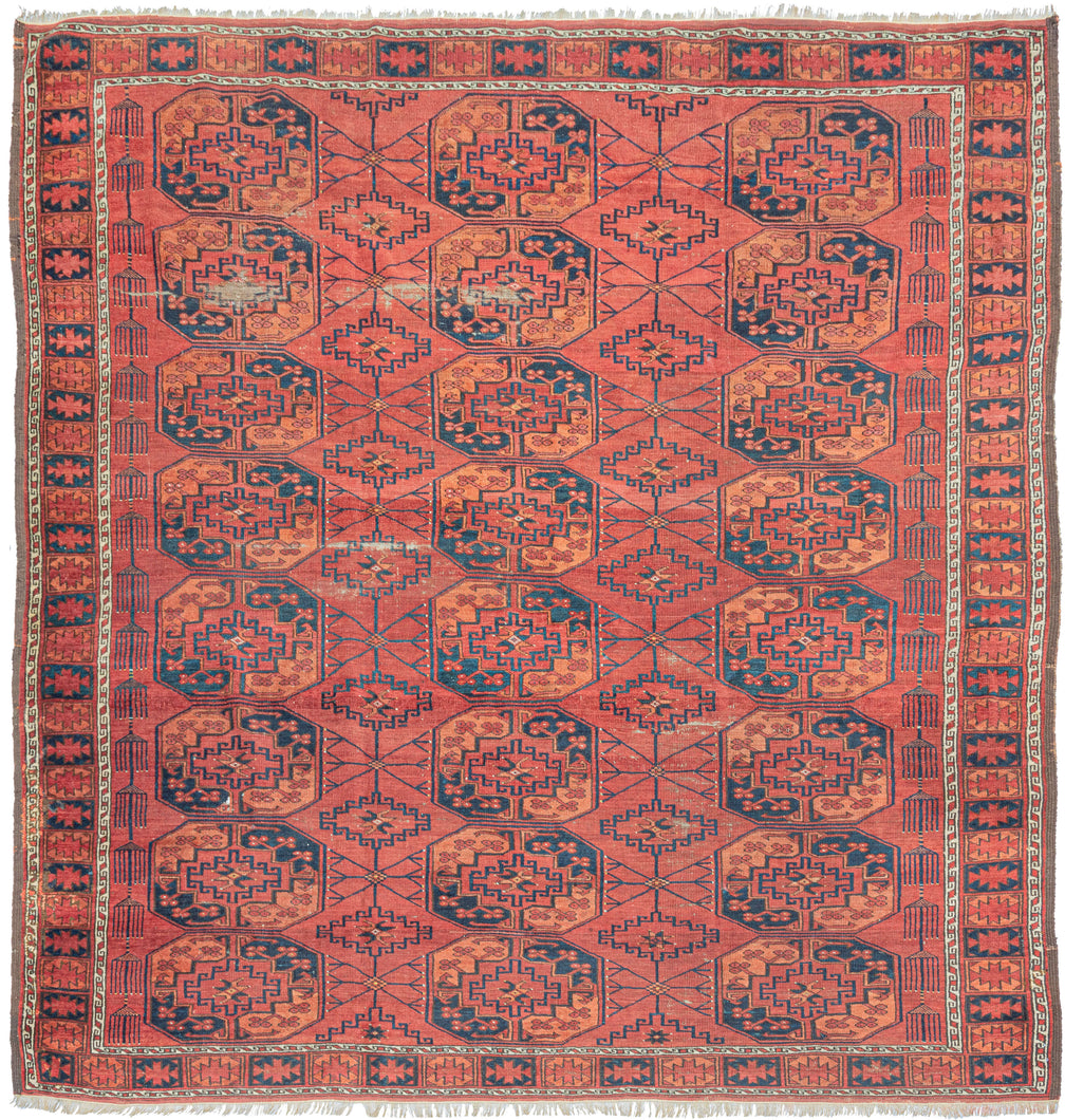 This Ersari Turkmen rug was woven in Northern Afghanistan.  It features a traditional Ersari gül design with a with soft palette of orange and indigo on an earthy madder red ground with accents of natural undyed brown and ivory wool. The secondary guls are more skeletal and interconnected by thin weblike lines. Of particular interest are two columns of amulets on either end of the field which add some distinction and serious interest to this usually straightforward design lexicon.