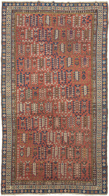 This Shirvan was handwoven during the early 20th century in the Eastern Caucasus.

It features an allover design in diagonal rows on an earthy red ground. The field is composed of tree-like forms each surrounded by rosettes. In between each tree-like form are a geometric flower and a form with opposing bird-like figures.