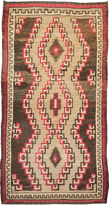 This Antique Navajo rug was handwoven in the Southwest USA during the first quarter of the 20th century.

This striking rug features jagged concentric lines vibrating from a small central diamond. The sharp angles and mottled tones of gray, brown, and red give the lines a dimensionality and they appear to float on the mottled gray inner field and variegated brown outer field. Framed by an inner dentil border and a red and brown serrated perimeter that has a flame like quality.
rare large size