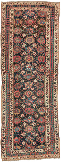 This rug was handwoven in Veramin during the early 20th century.

It features a classic mina khani design in a wide array of tones including red, pink, blue, green, purple and yellow which really pop against the deep surmah or blue/black ground. Uncharacteristically, a red and blue Laleh Abbasi pattern is utilized for the main border and flanked by ivory ground minor borders. Laleh Abbasi patterning is almost always used as a guard border around the perimeter of a rug. Other unique details include