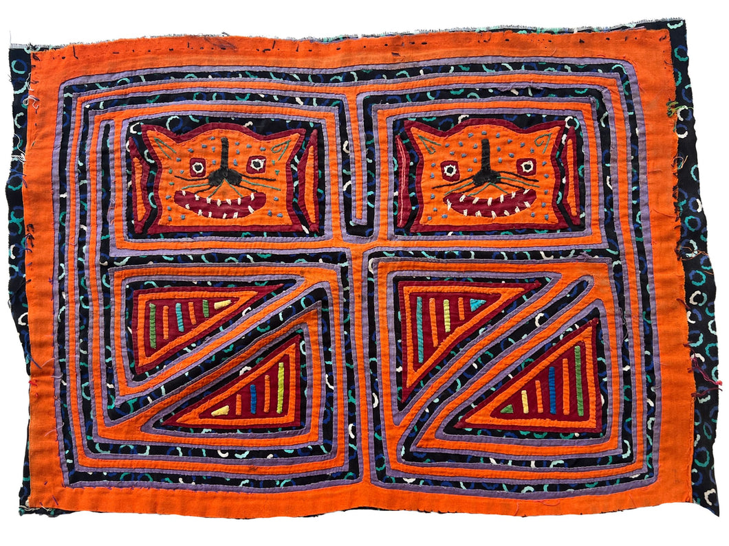 Vintage Mola cloth handmade by the Guna (previously spelled Kuna) people of the San Blas Islands.  Mola is a reverse appliqué technique, similar to the technique used in quilting but using multiple layers of different-colored cloth that are first sewn together before a design is created by cutting away different layers. These cloths are traditionally made in pairs to be worn on the front and back of women's blouses.  This Mola features two orange cats. 