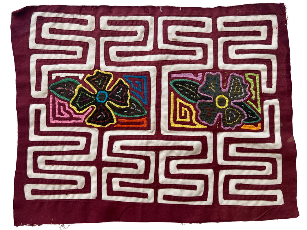 Vintage Mola cloth handmade by the Guna (previously spelled Kuna) people of the San Blas Islands.  Mola is a reverse appliqué technique, similar to the technique used in quilting but using multiple layers of different-colored cloth that are first sewn together before a design is created by cutting away different layers. These cloths are traditionally made in pairs to be worn on the front and back of women's blouses.  This Mola features a two central flowers.  The fabric is in good condition.