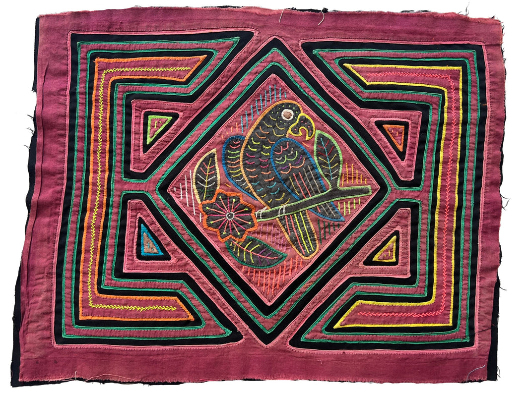 Vintage Mola cloth handmade by the Guna (previously spelled Kuna) people of the San Blas Islands.  Mola is a reverse appliqué technique, similar to the technique used in quilting but using multiple layers of different-colored cloth that are first sewn together before a design is created by cutting away different layers. These cloths are traditionally made in pairs to be worn on the front and back of women's blouses.  This Mola features parrot sitting on a branch. 