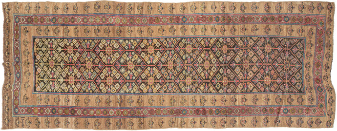 It features an allover lattice design of flowering shrubs in reds, blues, yellow, blue and aubergine on a dark brown ground. Uncommonly and to great effect a narrow red ground border of vibrant polychrome rosettes is sandwiched between two wider matching borders of simple blossoming flowers on a soft camel ground. The undulation and openness of the camel ground highlights the natural brown wool these rugs are famed for and gives the composition an open and grand feel. Serab