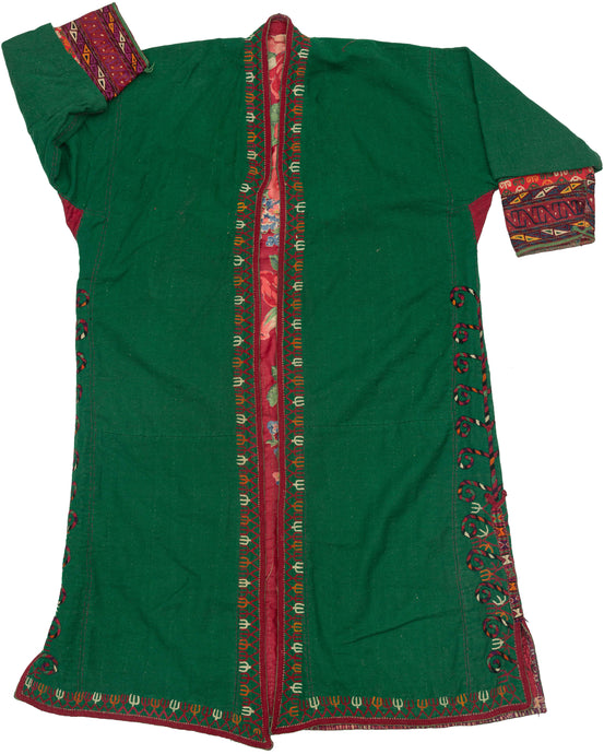 This lovely chapan is crafted from green wool. It is embroidered with an array of tones including black, red, white, orange and purple around its perimeter and up the sides. The tendrils of a tree of life or other plant form are found aroudn the slits on both sides. A red printed floral liner adds another element of interest. 