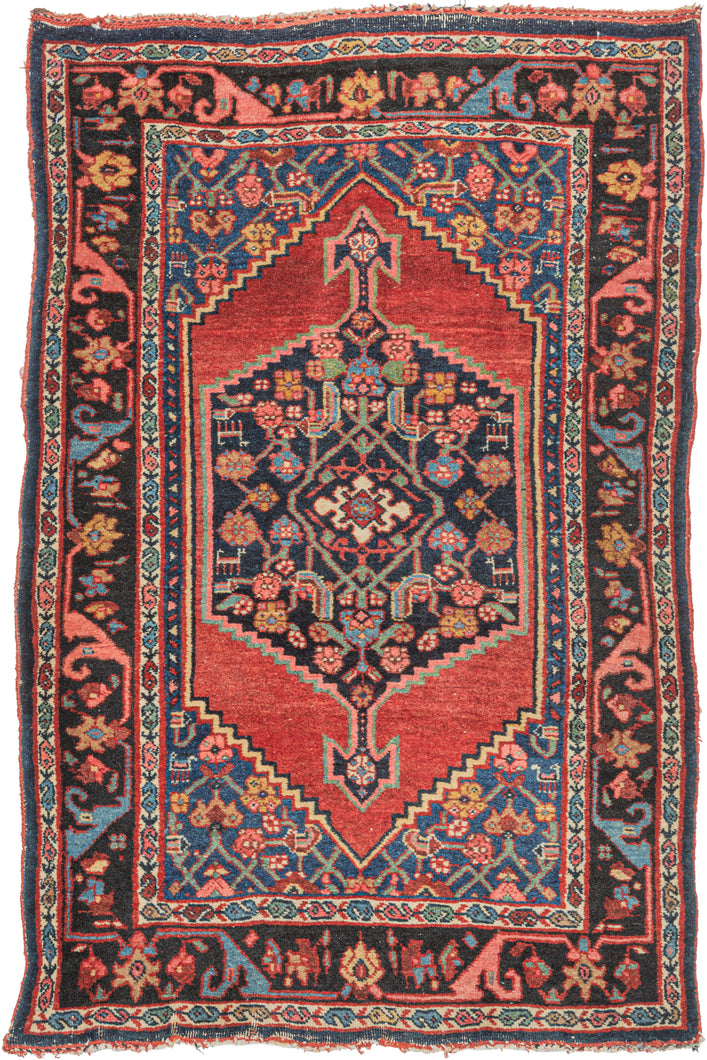 antique Persian Bidjar scatter rug featuring a midnight blue central medallion floating atop an open and undulating red lacquer field. A variation of the herati design can be found in both the medallion and the cornices which are rendered in blues, greens, pinks, and yellow. Upon closer inspection, various abstracted animals can be found in the pattern. 