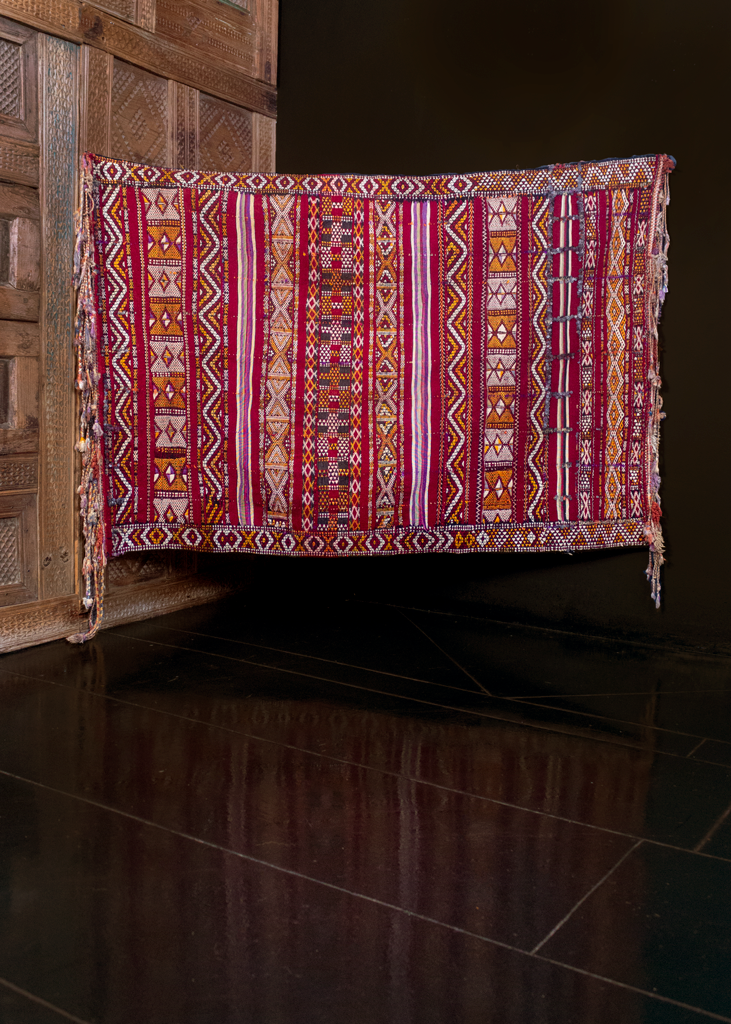 Hanbel rug handwoven during middle of 20th century in Morocco. Crafted on silk foundation with large bands of silk throughout. Horizontal rows of different geometric shapes. Maroon, red, ivory, purple and gold. Long braided silk tassels on either end. 