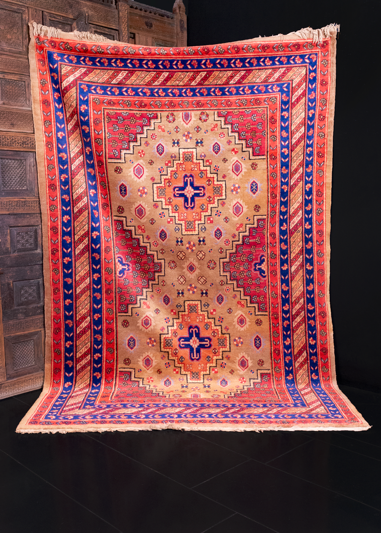 Khotan rug handwoven in Xinjiang region of Northwest China. Bold geometric patten with two medallions floating on a camel ground. Raspberry cornices filled with blue and orange flowers. 