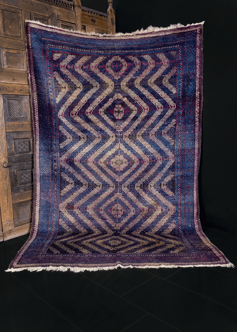 Mashwani Baluch rug handwoven in Afghanistan during second quarter of 20th century. Blue, ivory and purple field decorated with five curvilinear latch hook diamond medallions. 