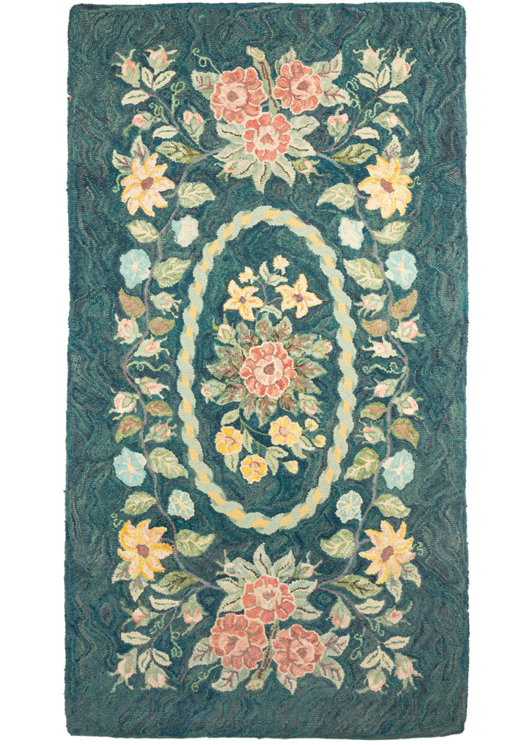 North American hook rug featuring a delicate floral design on a deep, undulating green field. A central spray of flowers in an oval medallion is surrounded by a symmetrical flower wreath. 