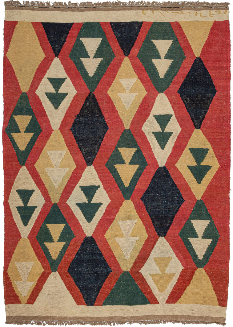 This Contemporary  Kilim features vertical columns of diamonds in yellow, green, ivory, and navy on red ground. The columns are staggered with most but all containing two stacked triangles which may be an abstraction of a vase or vegetal form. It is finished with a block of undyed ivory wool at the top and bottom. 