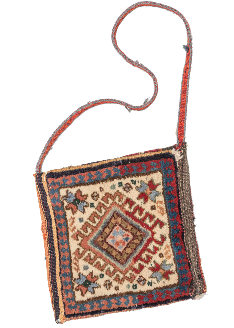 south Persian Shiraz chanteh shoulder bag feturing a pile front and flatwoven back. The pile design is composed of a central hooked diamond with four eight-pointed stars in each corner. The flatwoven back is composed of multicolored stripes in orange, red, blue, brown, and ivory. A colorful strap woven in orange and red completes the bag. 